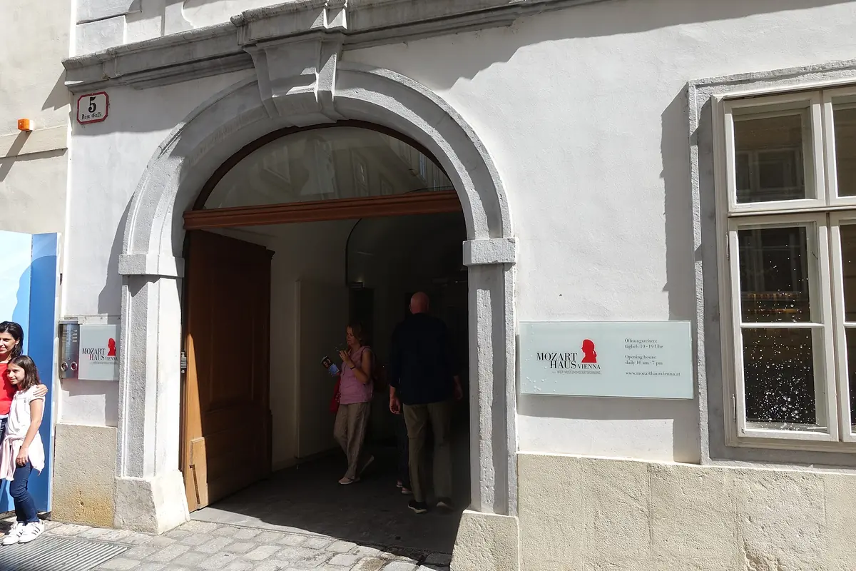 The arched doorway of the Mozarthaus Vienna museum at Domgasse 5, with the house number on the wall and visitors entering.